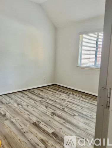 A room with wooden flooring and a window with blinds.