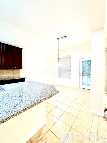 A kitchen with a granite counter top and tiled floor.