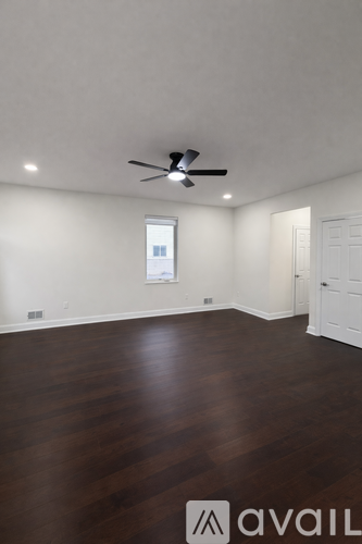 A room with a ceiling fan and wooden flooring.