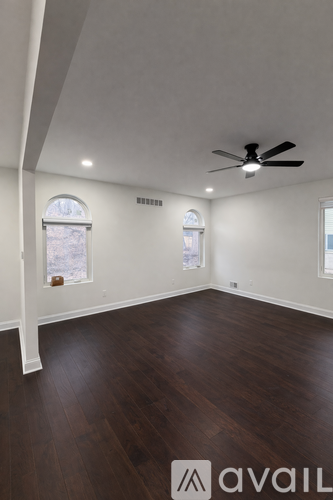 A room with a ceiling fan and two windows.