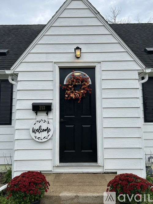 A white house with a black door and a wreath on the door.