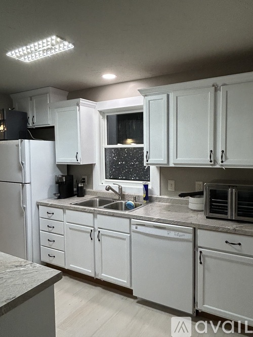 A kitchen with white cabinets and appliances.