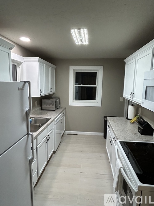 A kitchen with white cabinets and a refrigerator.