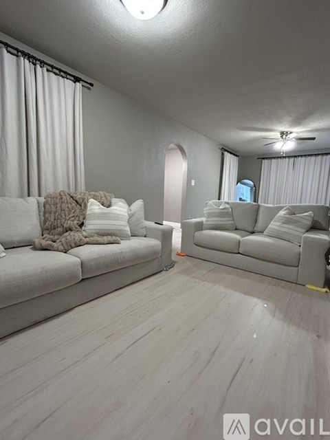 A living room with two couches and a ceiling fan.