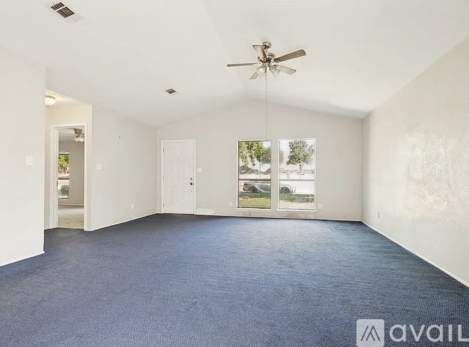 A spacious room with wooden floors and a large window.