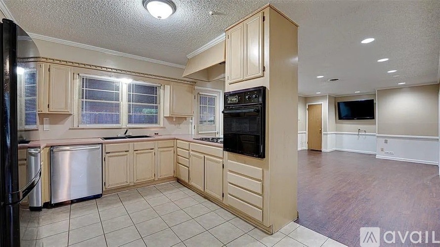 A kitchen with wooden cabinets and a black refrigerator.