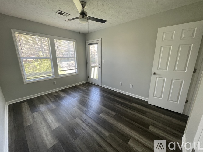 A room with a ceiling fan and wood flooring.