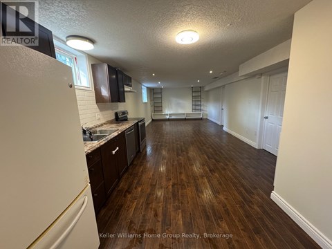 A spacious kitchen with dark wood floors and white walls.