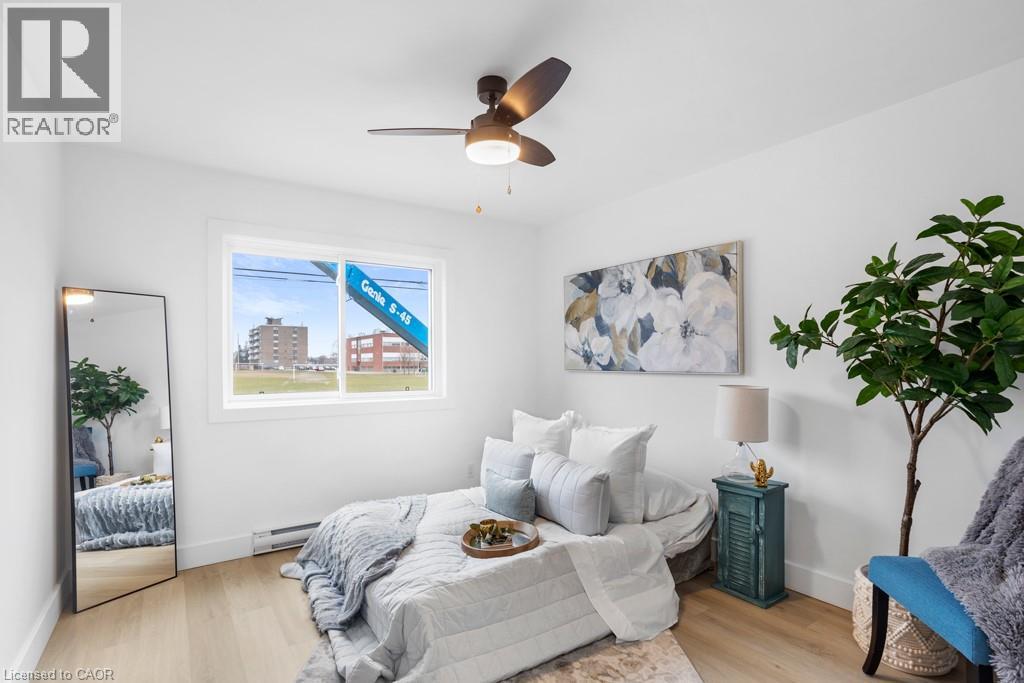 A bedroom with a bed, a ceiling fan, and a painting on the wall.