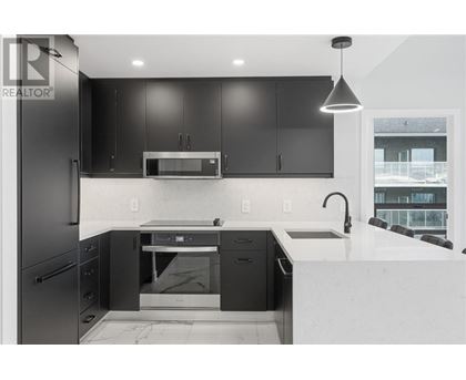 A modern kitchen with black cabinets and a white countertop.