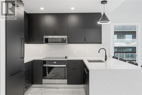 A modern kitchen with black cabinets and a white countertop.