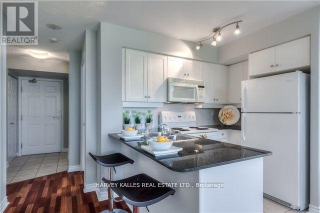 A kitchen with a refrigerator, microwave, and stove top oven.
