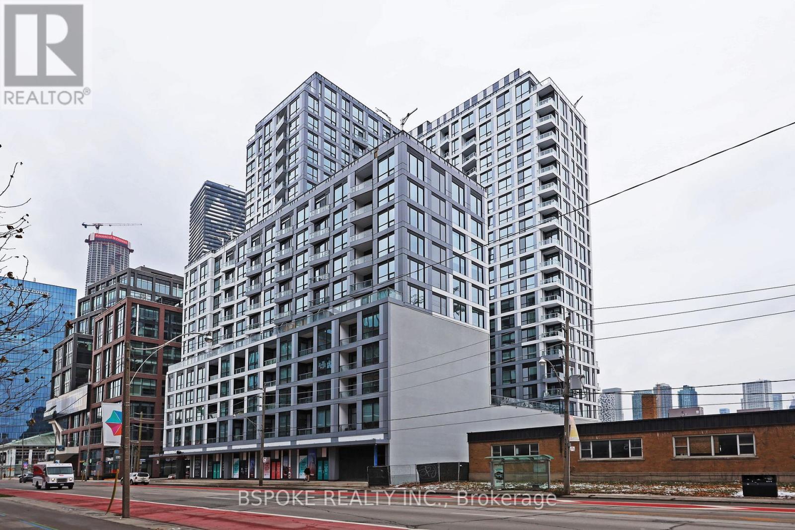 A modern building with a glass facade stands in the foreground of a city street.