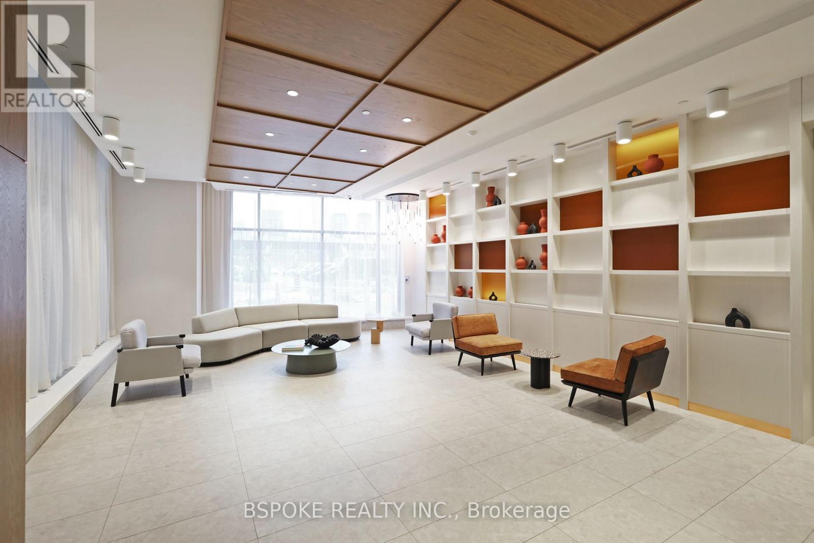 A spacious waiting area with white furniture and a large window.