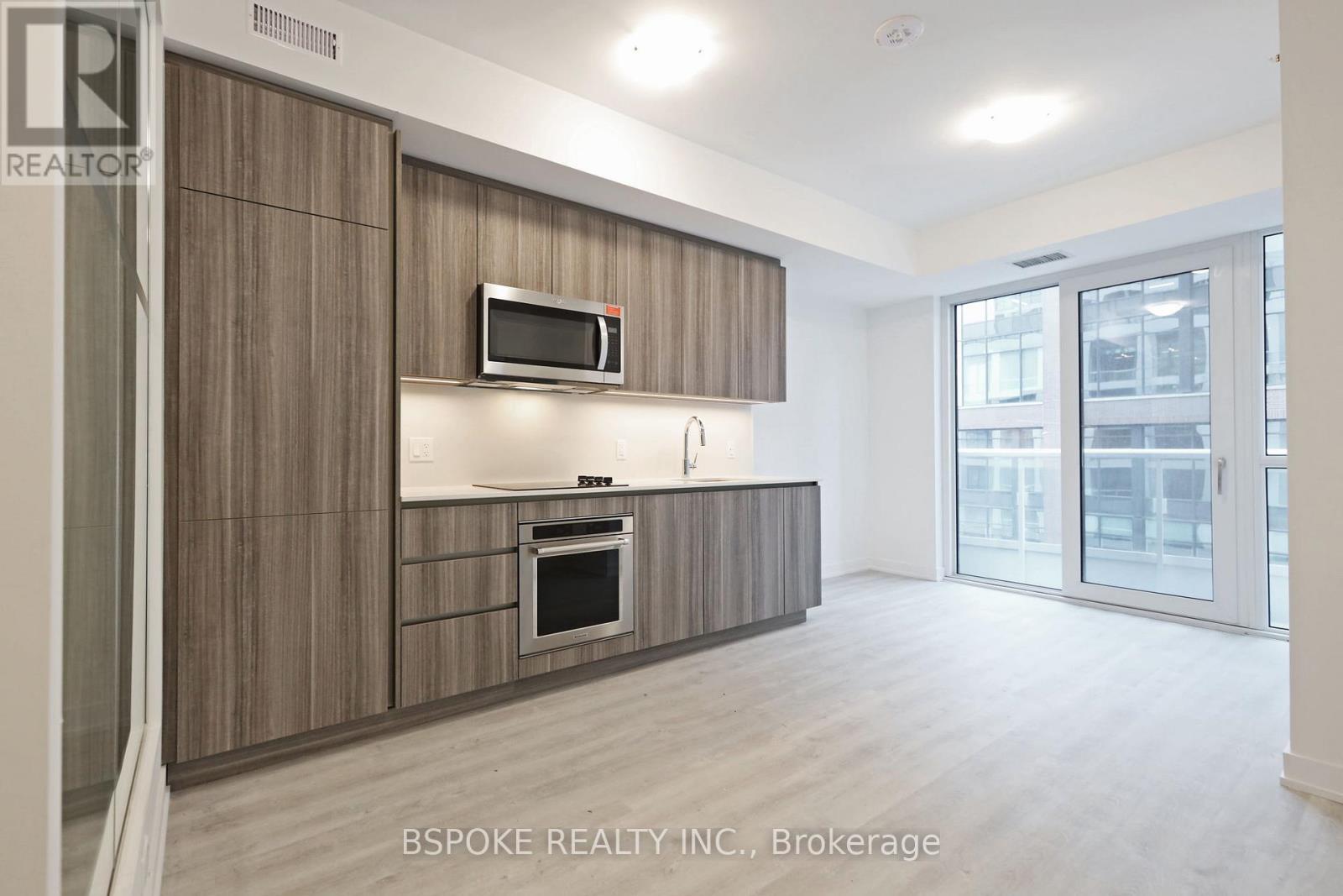 A modern kitchen with wooden cabinets and a microwave above the oven.