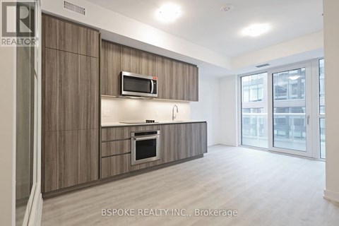 A modern kitchen with wooden cabinets and a microwave above the oven.
