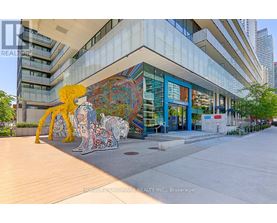 A large, colorful mural of a human figure is displayed in front of a modern building.