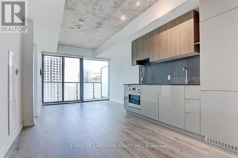 A spacious kitchen with white cabinets and a large window.