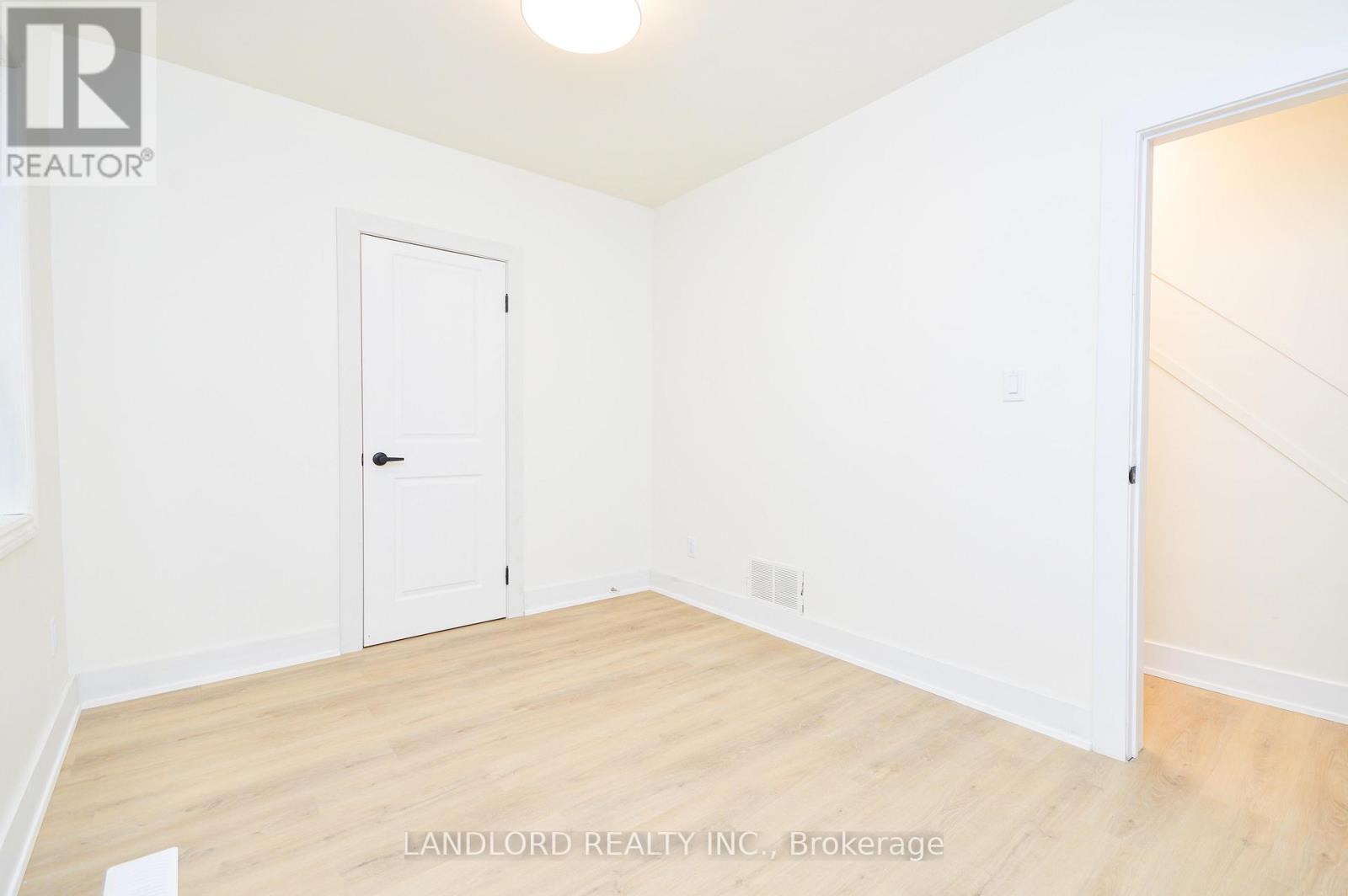 A white door is in a room with wood floors and white walls.
