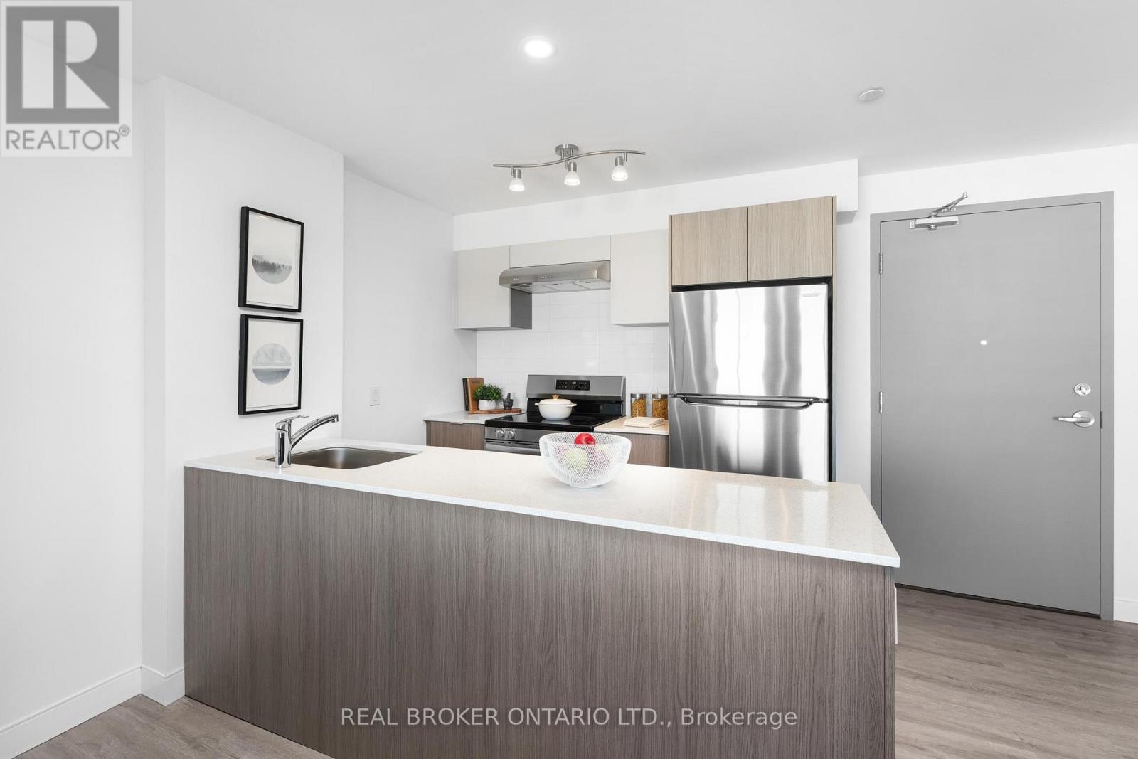 A modern kitchen with a stainless steel refrigerator and a sink.