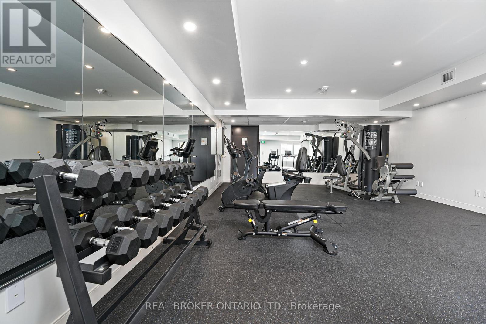 A gym with a variety of equipment including dumbbells, weight machines, and a bench press.