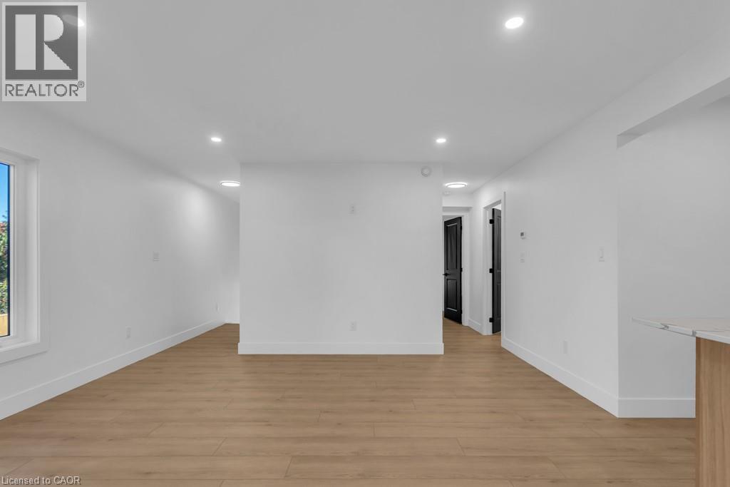 A spacious room with wooden flooring and white walls.