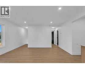 A spacious room with wooden flooring and white walls.