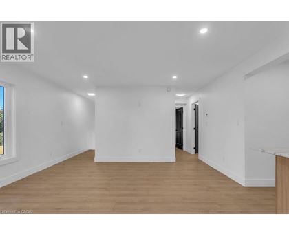 A spacious room with wooden flooring and white walls.