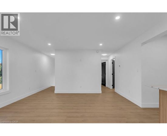 A spacious room with wooden flooring and white walls.