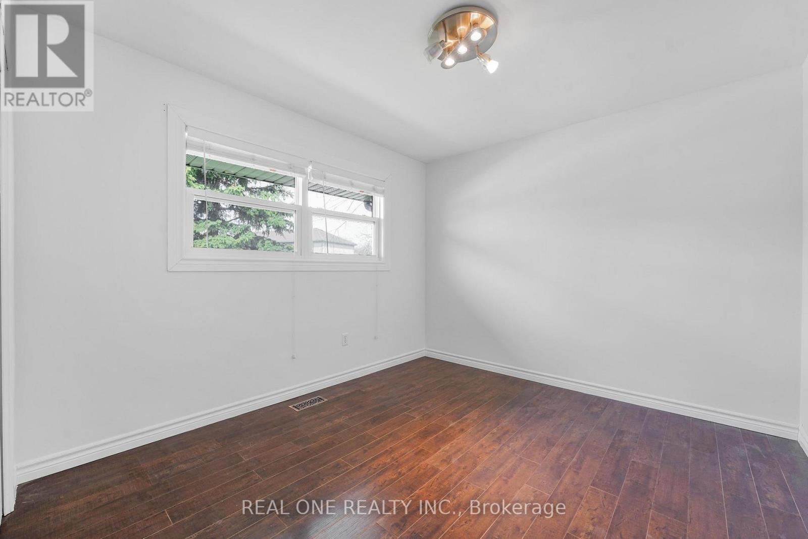 A room with white walls and a window with a view of trees.