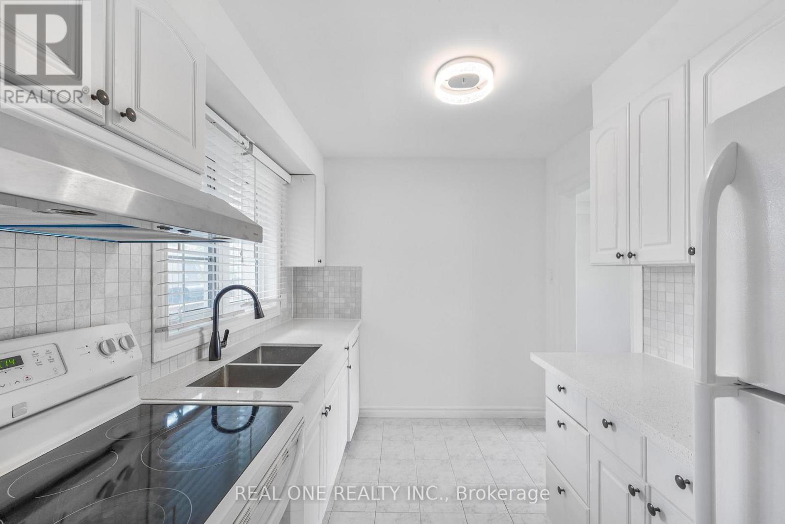 A white kitchen with a stove top oven and a refrigerator.