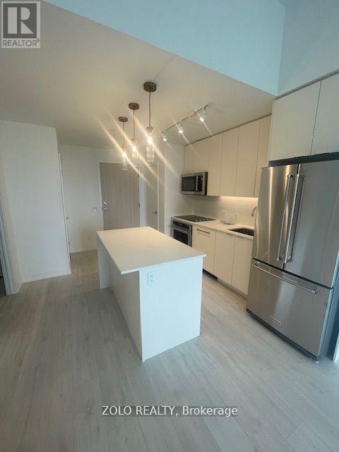 A modern kitchen with a white island and stainless steel appliances.