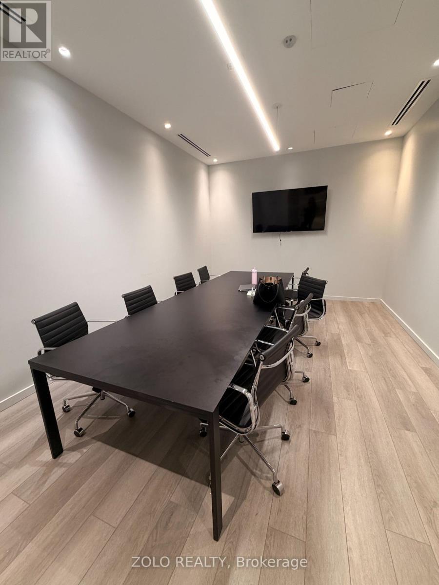 A conference room with a long table and chairs, and a television mounted on the wall.