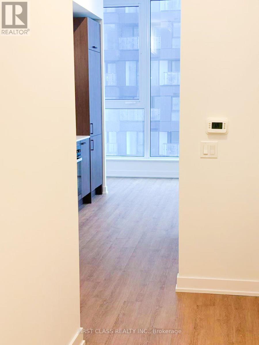 A room with a wooden floor and a window overlooking a building.