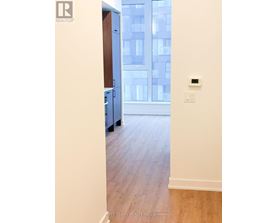 A room with a wooden floor and a window overlooking a building.