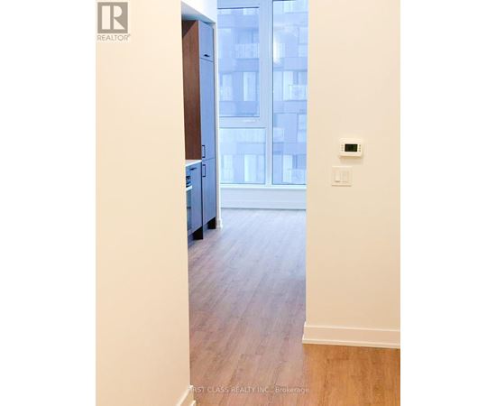 A room with a wooden floor and a window overlooking a building.