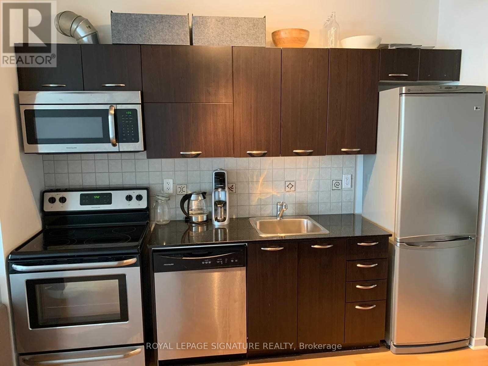 A kitchen with a stove, oven, microwave, sink, and refrigerator.