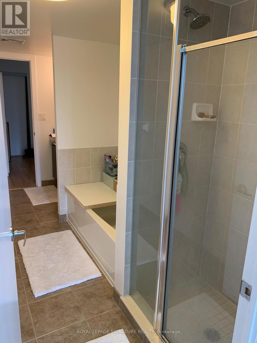 A shower area with a glass door and a white mat on the floor.