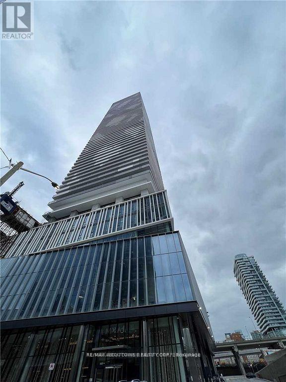 A tall building with a pointed top and a glass facade.