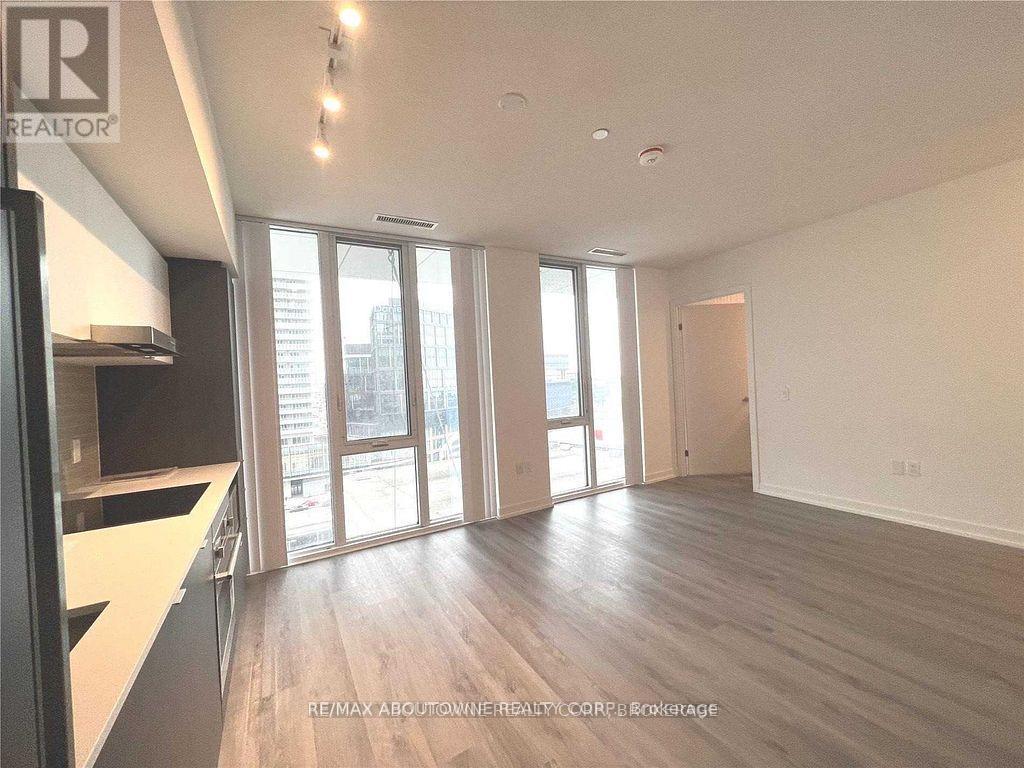 A spacious room with wooden floors and large windows.