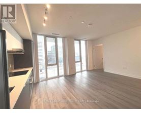 A spacious room with wooden floors and large windows.