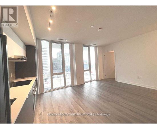 A spacious room with wooden floors and large windows.