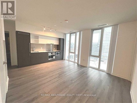 A spacious living room with hardwood floors and large windows.