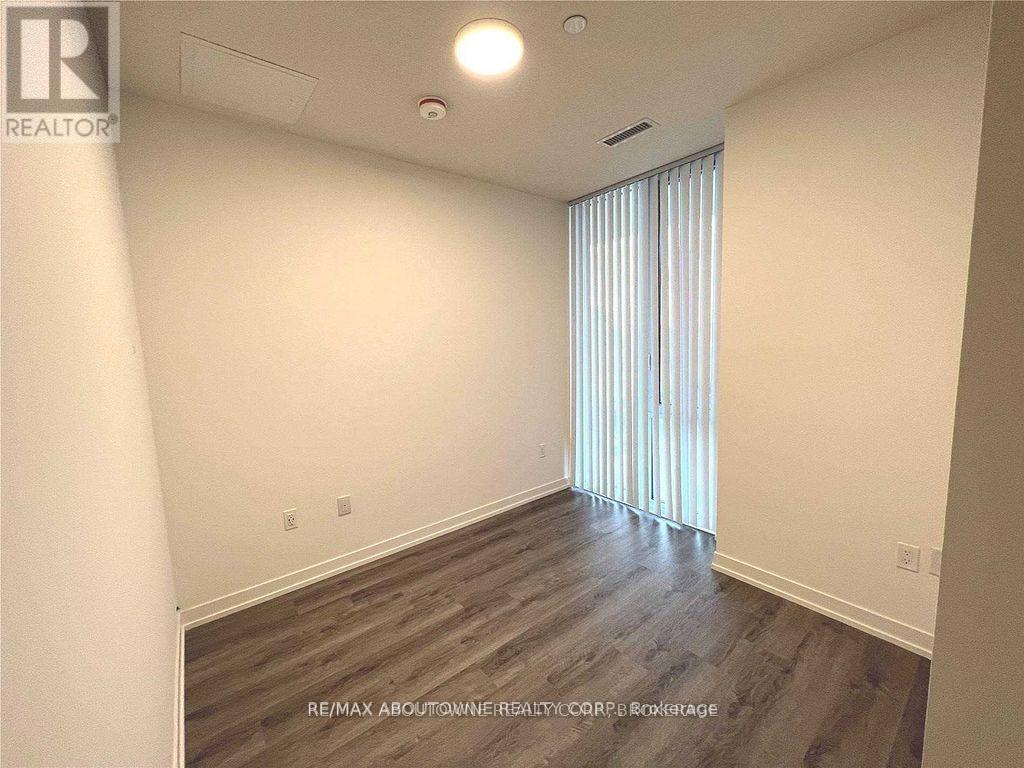 A room with wooden flooring and a window with blinds.