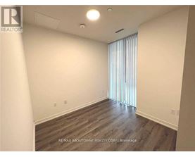A room with wooden flooring and a window with blinds.