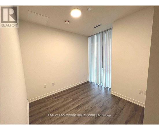 A room with wooden flooring and a window with blinds.