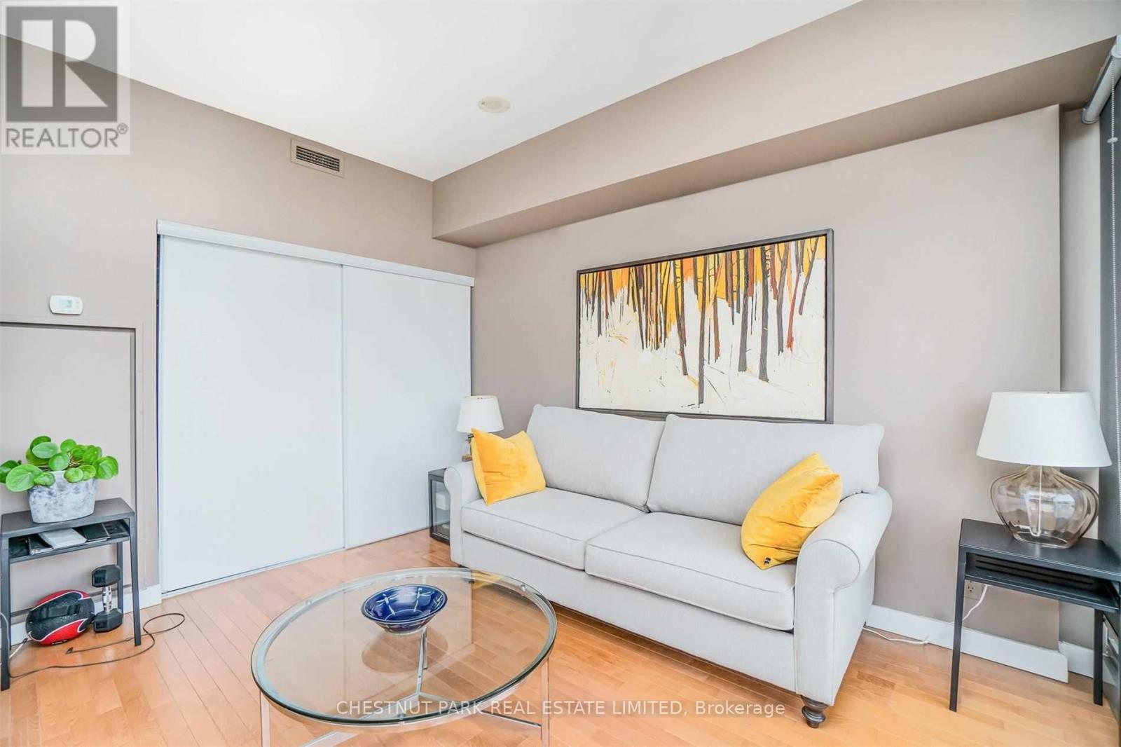 A living room with a white couch and a painting on the wall.