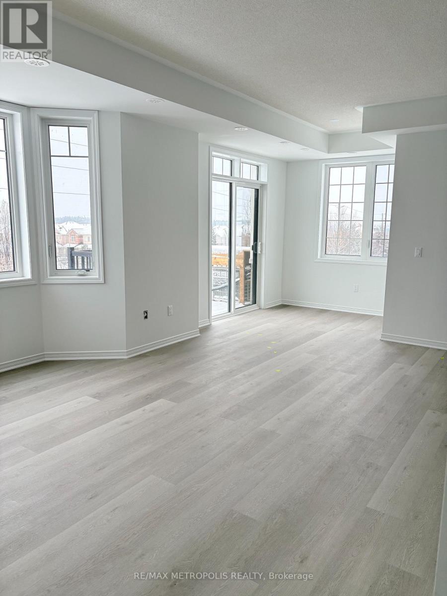 A spacious room with light wood flooring and white walls.