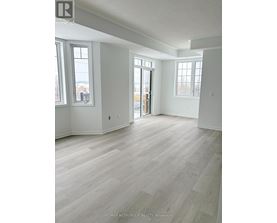 A spacious room with light wood flooring and white walls.