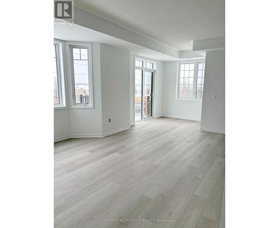 A spacious room with light wood flooring and white walls.